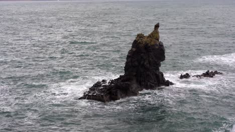 single impressive rock formation rising from ocean in iceland