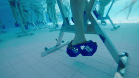 close underwater shot of a man pedaling on an aqua bike in a swimming pool