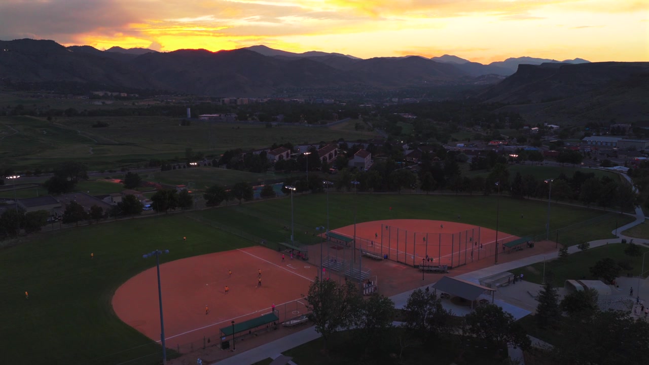 Softball players under lights Ulysses Sports Complex Field City of Golden aerial drone Colorado summer sunset Rocky Mountains Front Range foothills Clear Creek Canyon South Table Mountain upwards