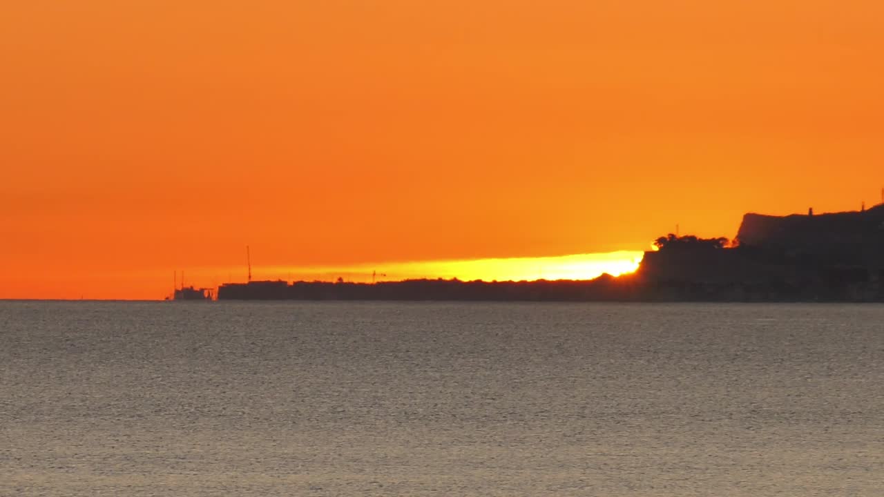 Sun rising over headland and calm seas, Spain