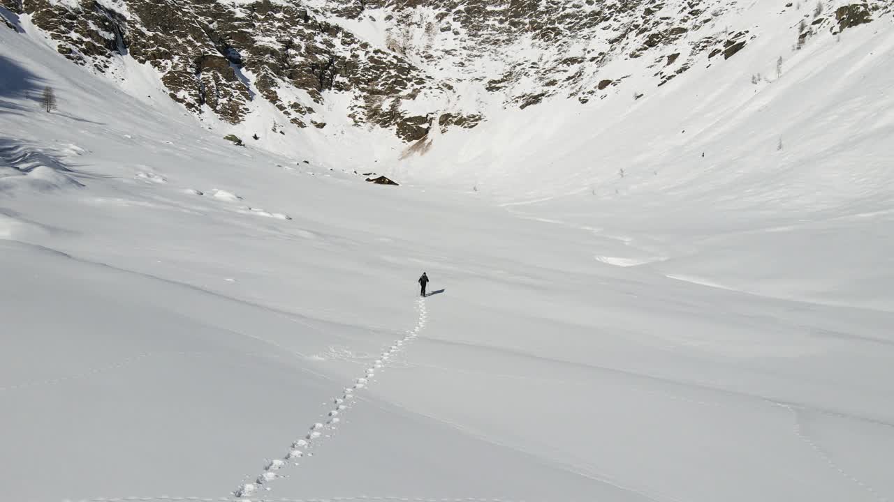 un hombre soltero está caminando en medio de las nevadas montañas italianas con sus raquetas de nieve