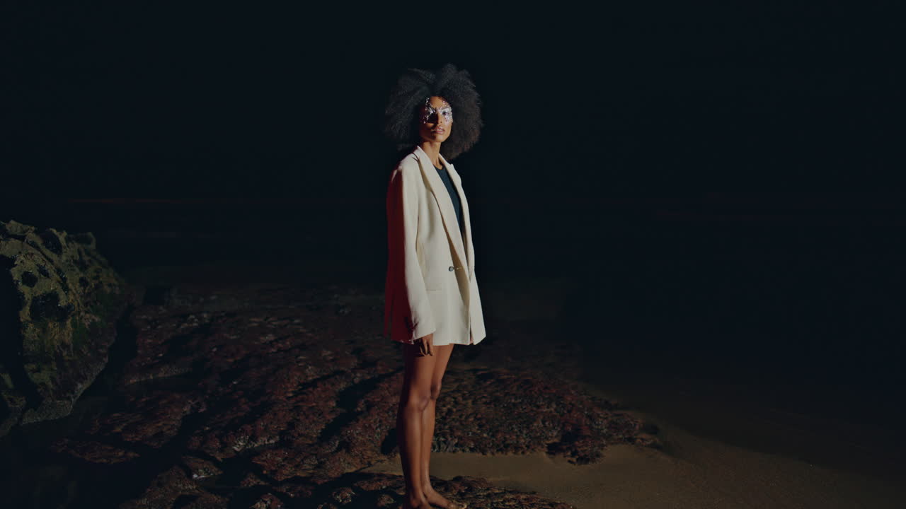 Glamorous model posing shore rocks at night. Trendy slim woman on dark beach