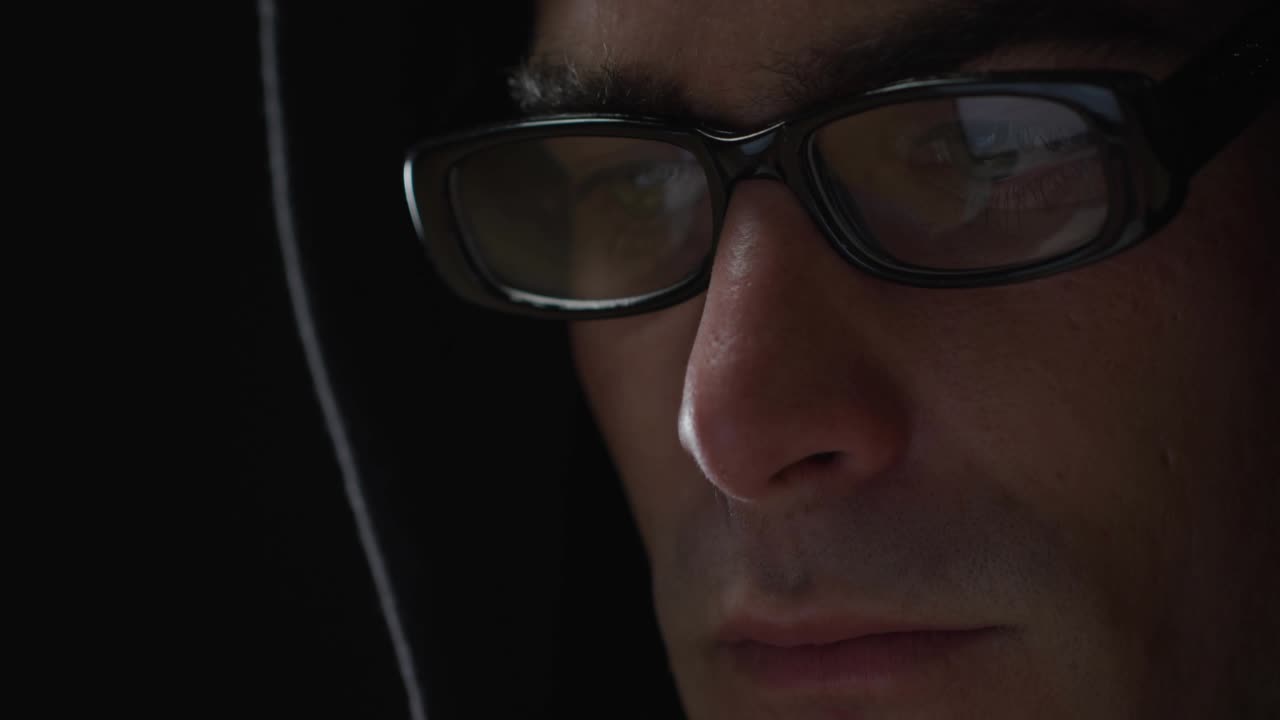 Hombre sentado en un laboratorio tecnológico analizando un monitor brillante que emite una línea de escaneo, animando iconos de cuadrícula de datos