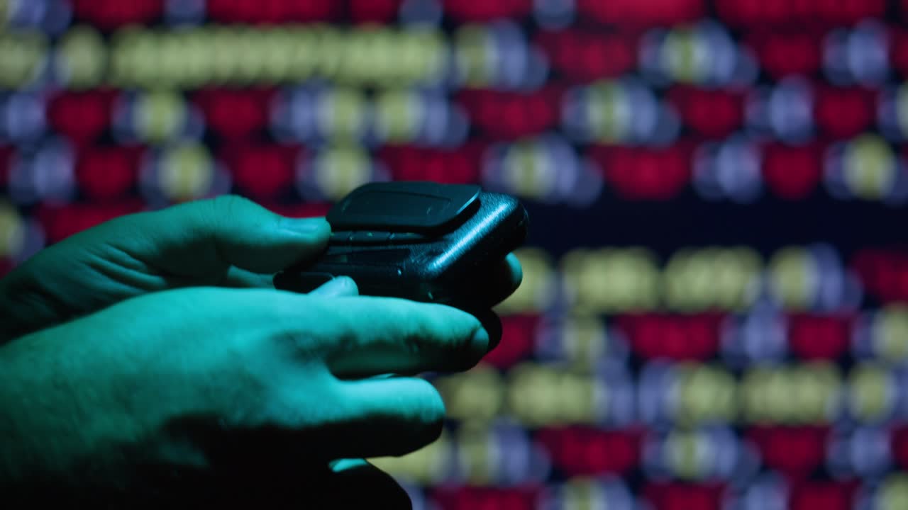 persona usando un viejo teléfono celular frente a un fondo de código borroso.