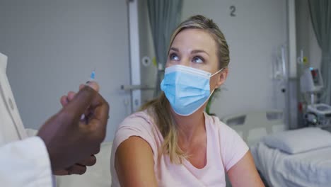 caucasian female patient wearing face mask sitting in hospital bed waiting for injection