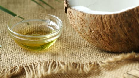 una rebanada de coco fresco y una botella de aceite en una mesa
