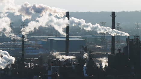 industrial landscape with smokestacks emitting steam against a clear sky, distant view