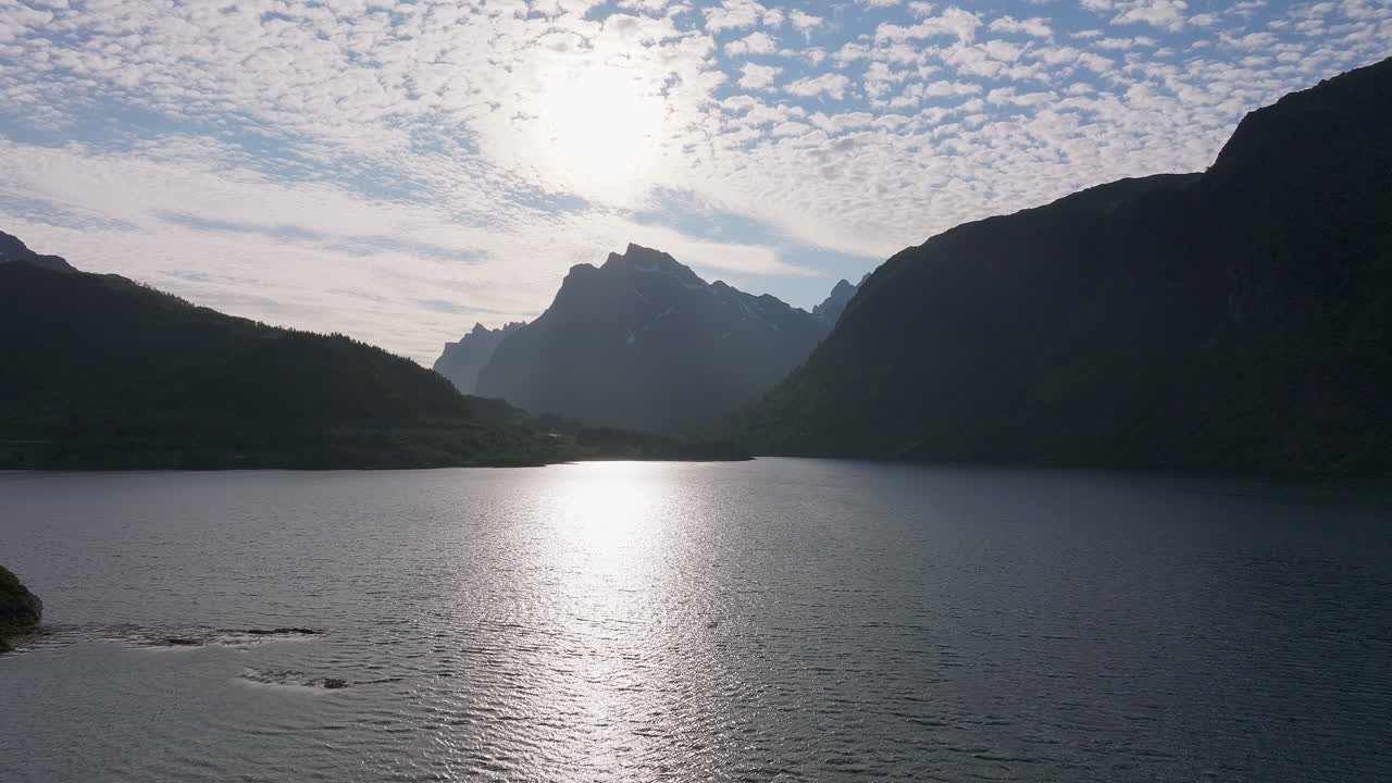 드론 은 웅장 한 산맥 의 실루 ⁇  과 함께 평화로운 해양 풍경 을 날아다니고 있다