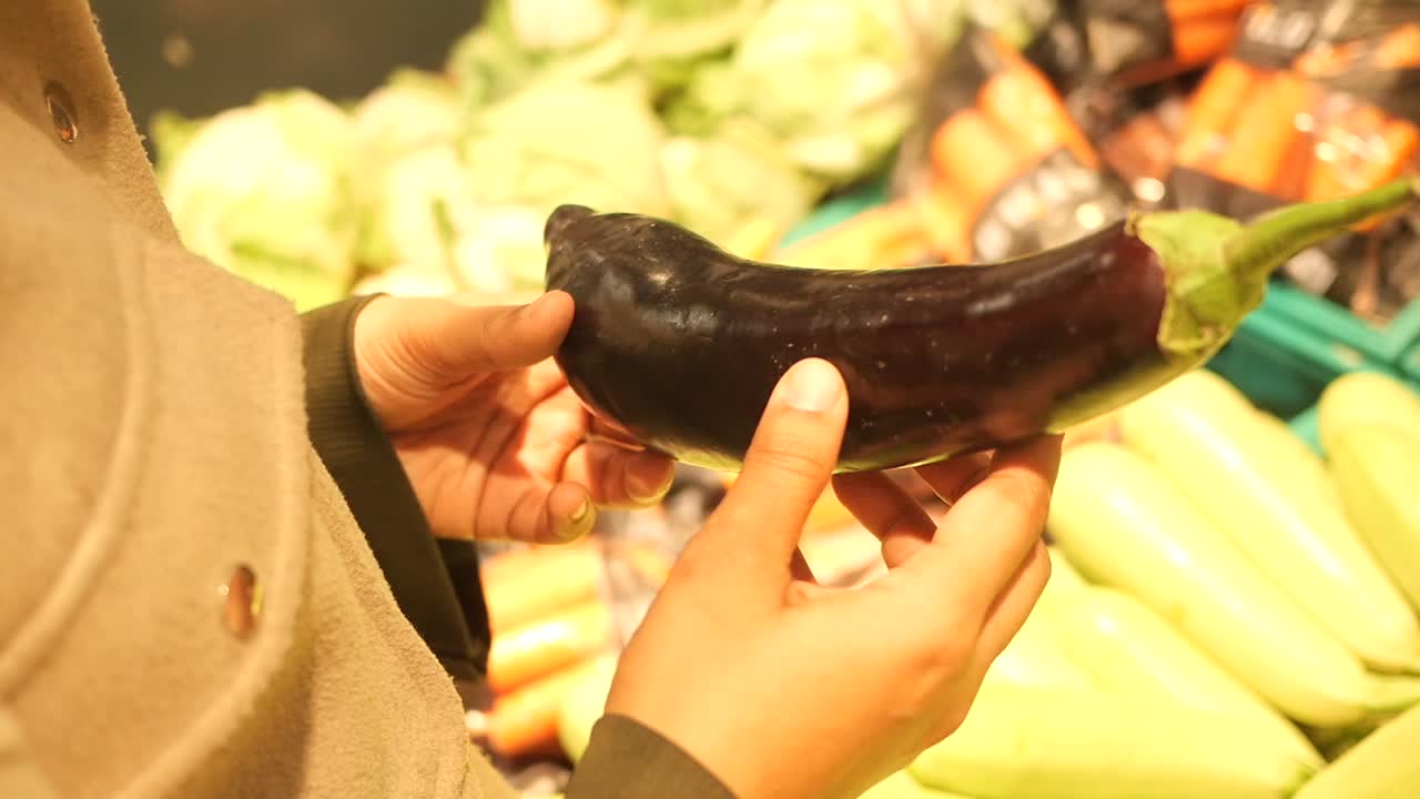 Person buying an eggplant at a grocery store