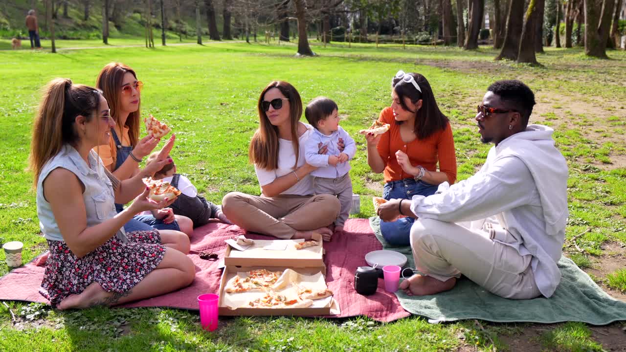 Group of Friends and Family Enjoying a Picnic with Pizza in the Park