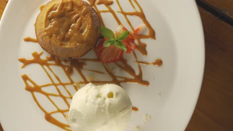 Rotating-plate-with-Dulce-de-Leche,-Caramel-Volcano-with-ice-cream-and-strawberry-garnish,close-up---top-view