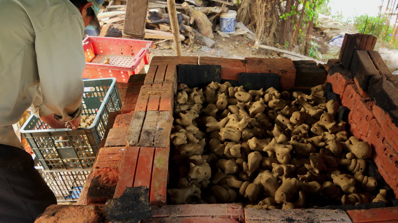 한 남자가 갓 만든 동물 모양의 점토 피리를 쌓아 발사 준비를 하고 수제 악기의 아름다움과 장인 정신을 보여줍니다.