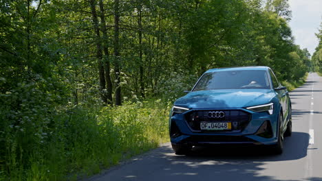 light blue automobile on a road. modern audi e-tron driving on a highway for saving environment. test drive of a luxury electronic car model.