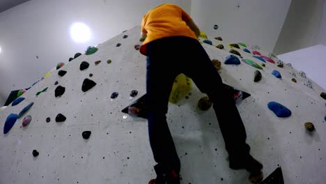 boulder gym climbing wall seen right from below as a climber approaches and climbs up and then down with no rope