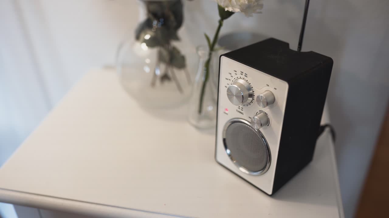 오래된 흰색 라디오-1을 켜는 노란색 스웨터를 입은 여성을 보여줍니다.