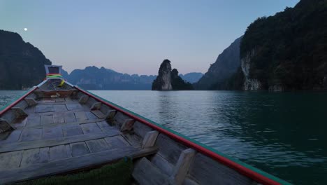 capturing the tranquil beauty of khao sok national park in surat thani, thailand, from a moving tour boat gliding over the water's surface during the evening