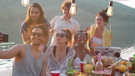 joyous friends taking selfie at lake party