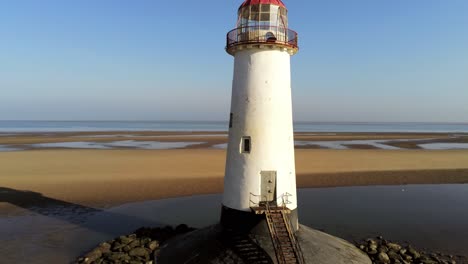 Talacre-lighthouse-golden-sandy-ocean-coastline-during-low-tide-sunrise-aerial-rising-view