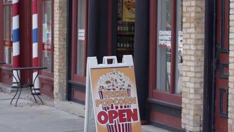 Cravings-Gourmet-Popcorn-and-Soda-Pop-Market-store-sign-in-Lansing,-Michigan-Old-Town-with-video-tilting-down-wide-shot