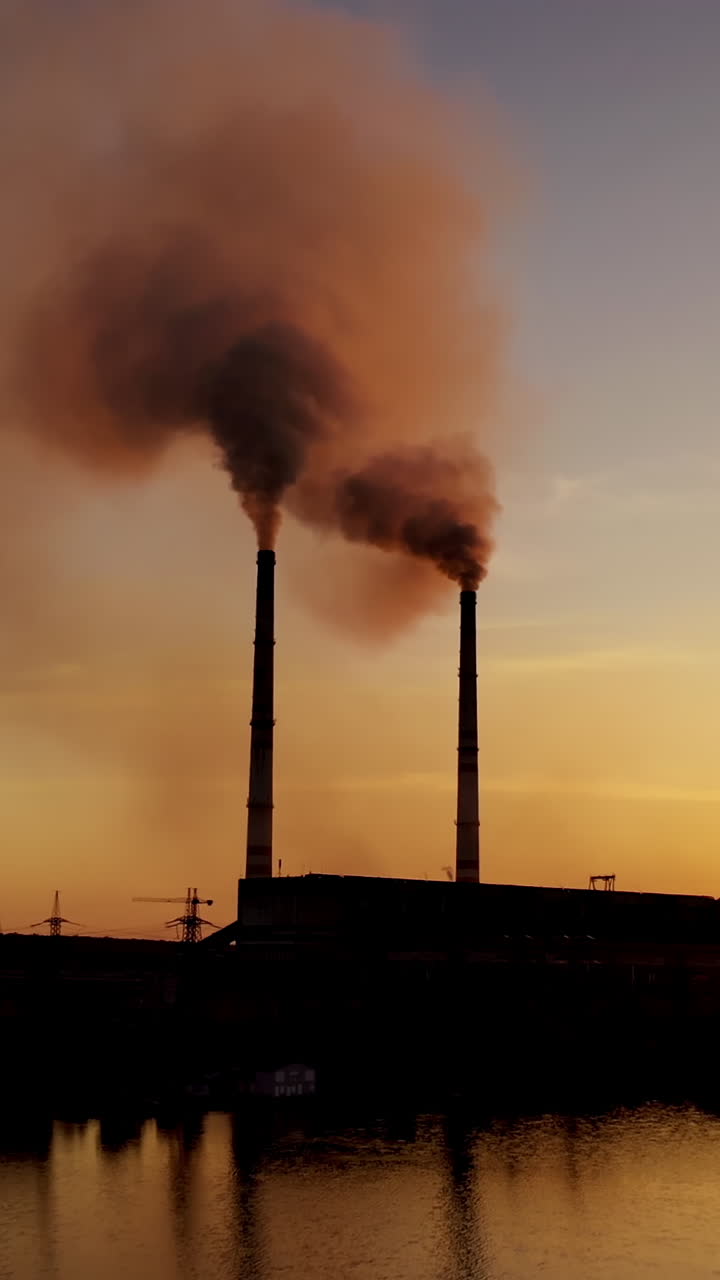 Smoke from pipes in factory. Industrial factory buildings from the outside Vertical video