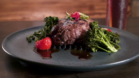 perfectly grilled 8 oz prime filet mignon on a bed of broccolini with stuffed cherry peppers plated on black rustic stoneware plate, slider hd