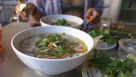 hermosa mujer en bikini comiendo sopa de fideos con ternera pho tradicional vietnamita en un restaurante local