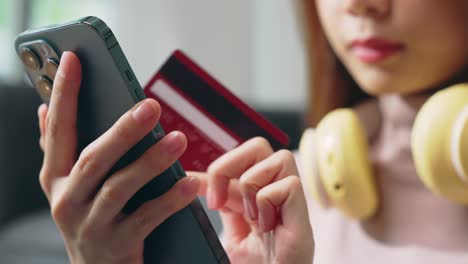 young asian woman holding credit card and using smartphone for shopping online with payment on internet banking.