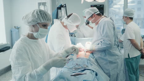 surgeons with team operate patient heart. female assistant prepares sterile medical instrument during coronary artery bypass graft surgery in hospital