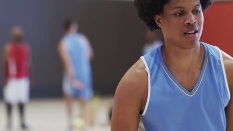 feliz jugador de baloncesto afroamericano girando la pelota en el dedo en la cancha cubierta, cámara lenta