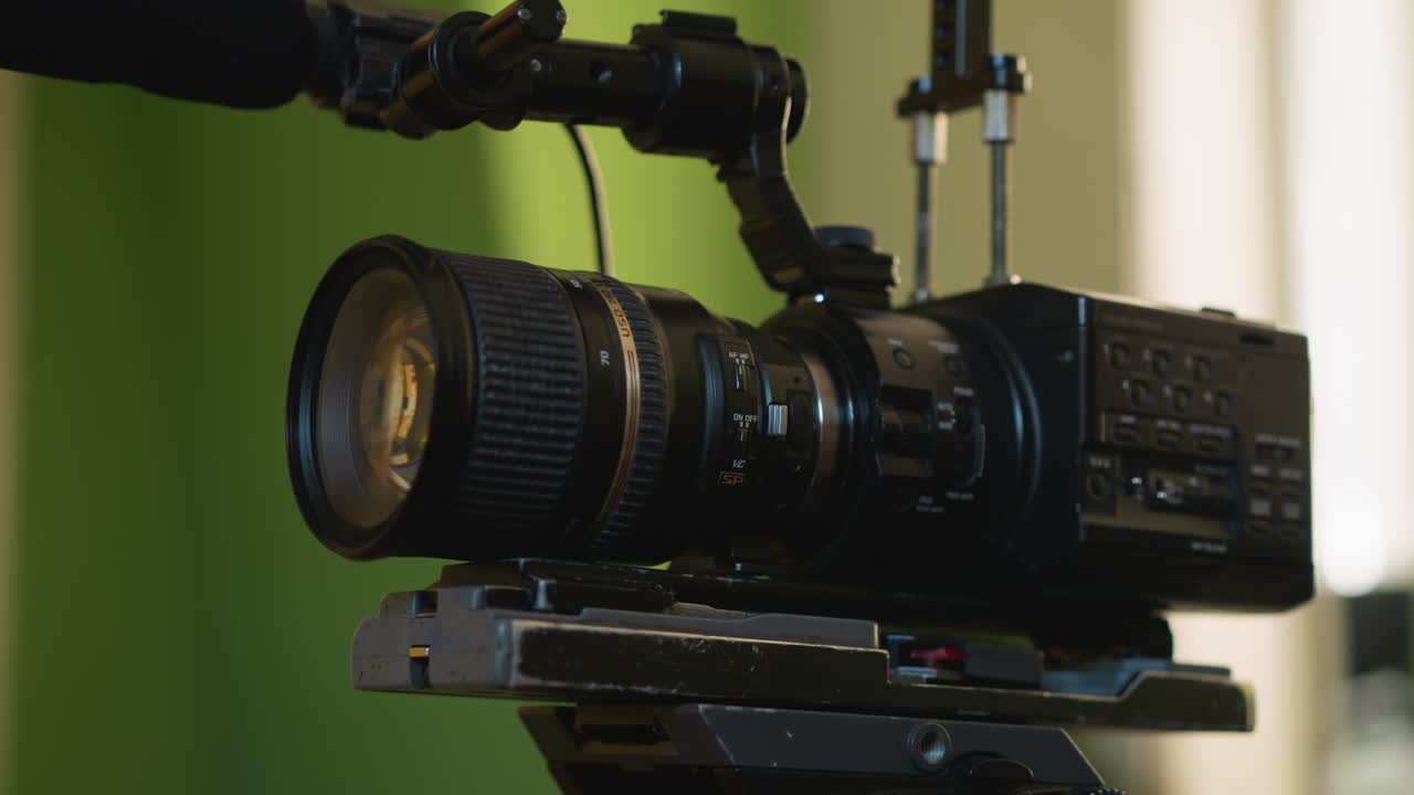 cameraman's hand adjusting camera in film production, close-up shot capturing detailed focus on lens, filming setup in studio, video production in progress, professional crew at work