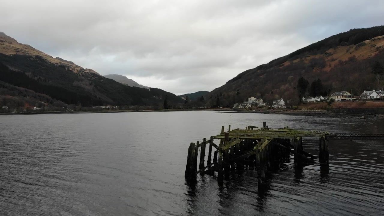 Low Aerial Flyover of Abandoned Wooden Pier Ruins on Loch Long in Arrochar Scotland