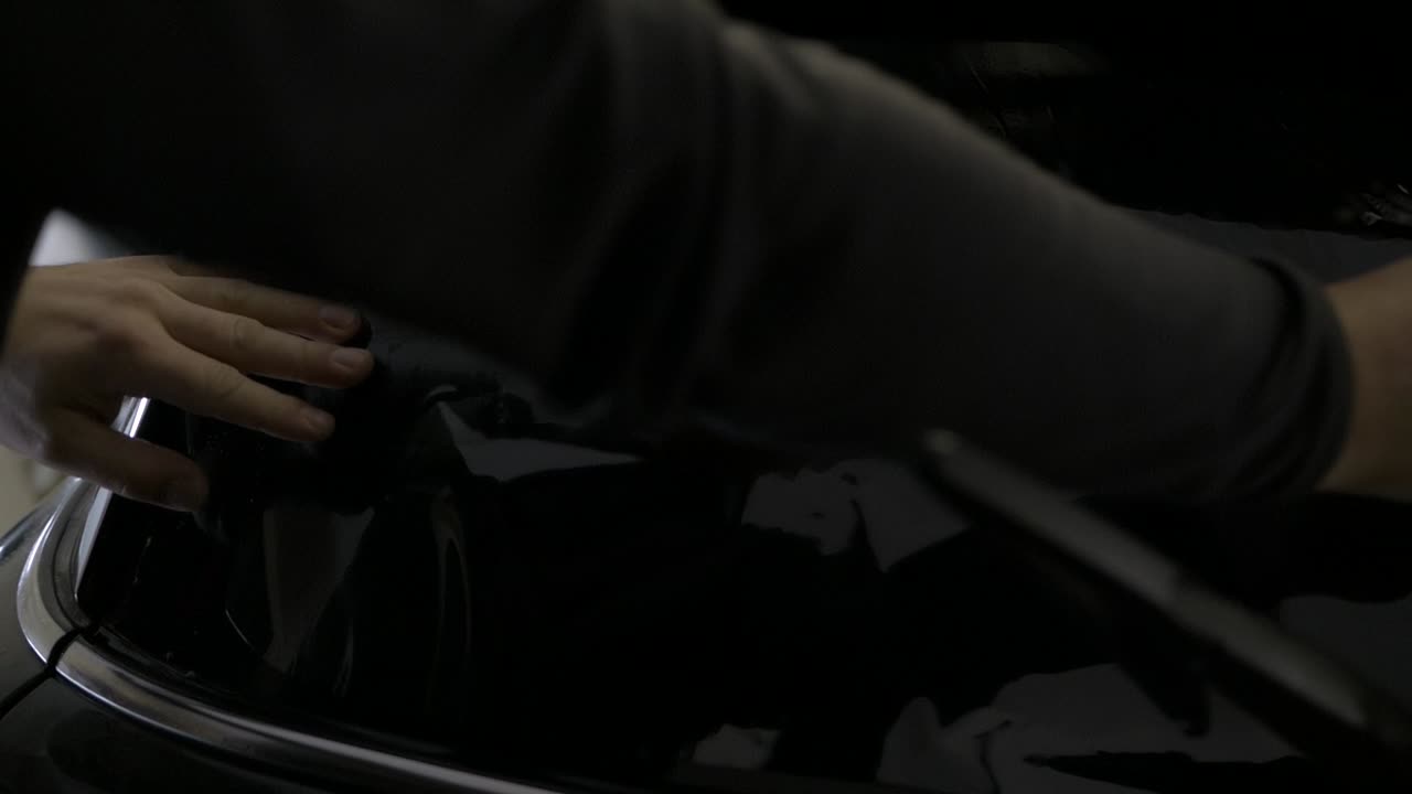 Air bubbles being pushed out of window tinting foil on car rear window