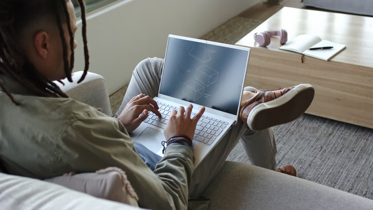 Adult bringing hands to keyboard, initiating typing on laptop with blueprint, headphones resting