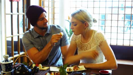 man feeding sushi to woman