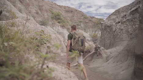 Rear-View-Of-A-Male-Backpacker-Walking-Through-Steep-And-Narrow-Canyon-Hiking-Trail