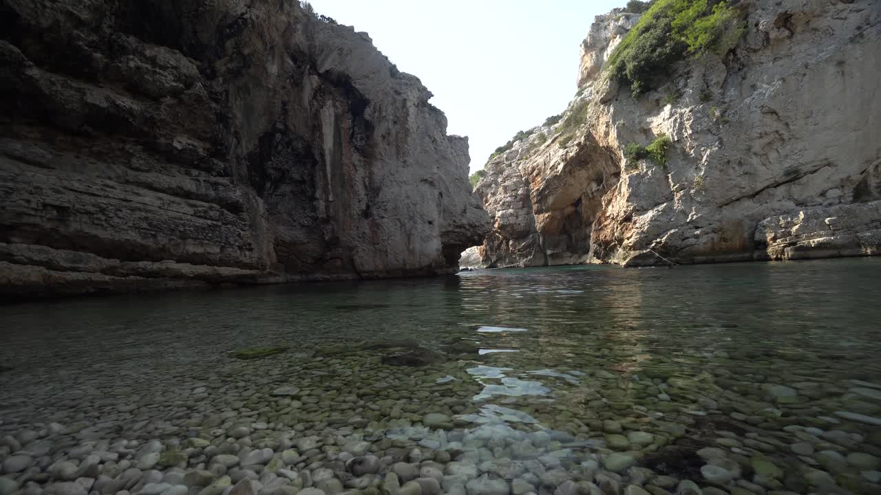 vista en ángulo bajo del agua clara del mar en una cala sombreada y apartada escondida por altos acantilados a lo largo de la costa de croacia