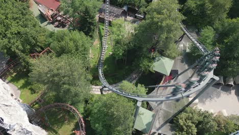 roller coaster carriage reaches peak on track and rushes down turning hard and rising, aerial tracking