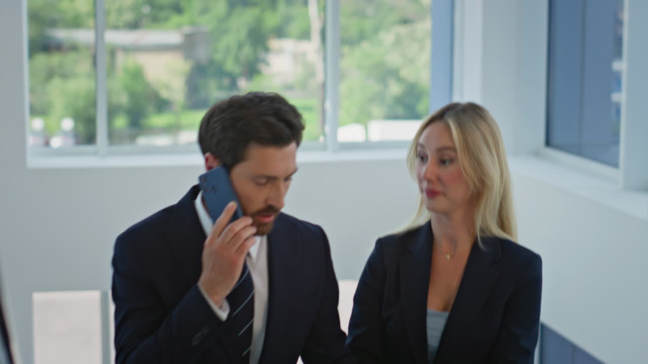 Walking businesspeople reviewing documents at modern office staircase closeup