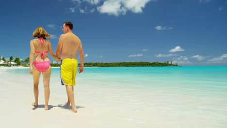 barefoot caucasian couple holding hands on tropical beach