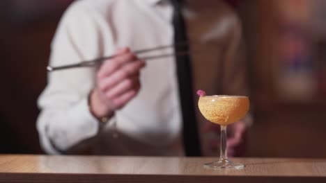 Close-up-of-alcoholic-cocktail-and-blurred-background-of-a-barmen-decorating-it