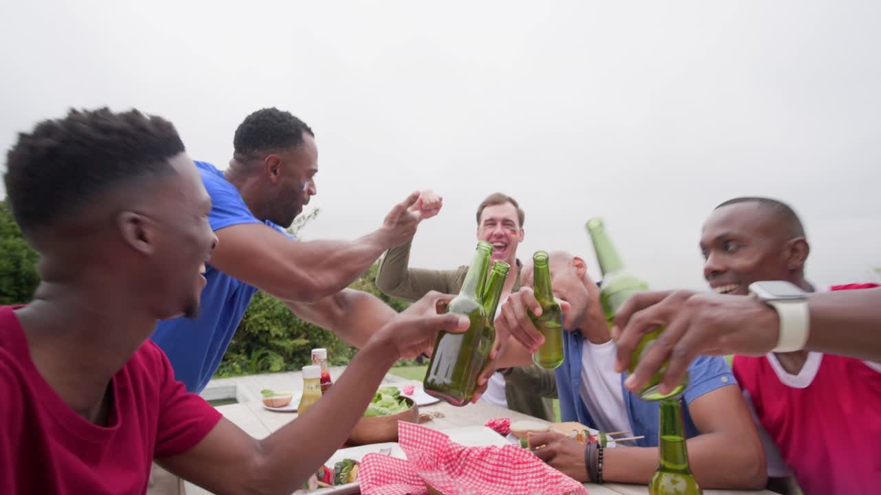 Diverse mannelijke vrienden reiken naar de telefoon voor een selfie, leunen en proosten met groene biertjes in de tuin.