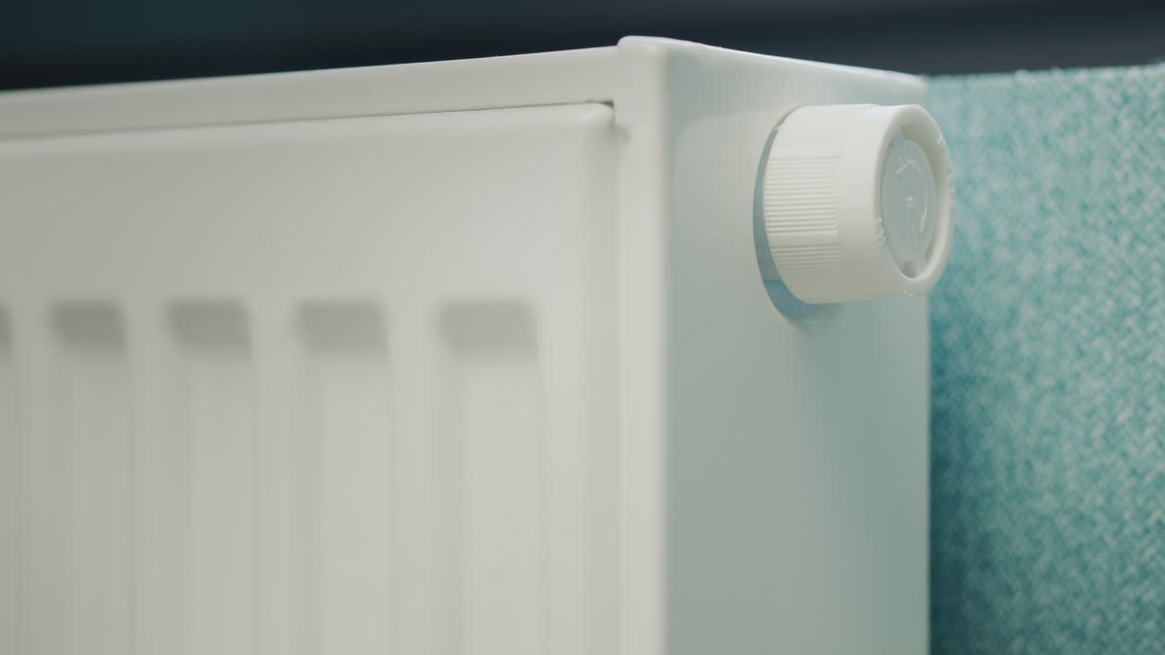 A man's hand regulates the temperature on a heating radiator. Conservation of energy resources in a private house