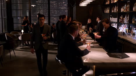 people socializing and enjoying drinks at an upscale bar or lounge at night