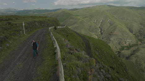 fotógrafo de viajes caminando por un paso de montaña con una cámara en el hombro cerca de borjomi en georgia