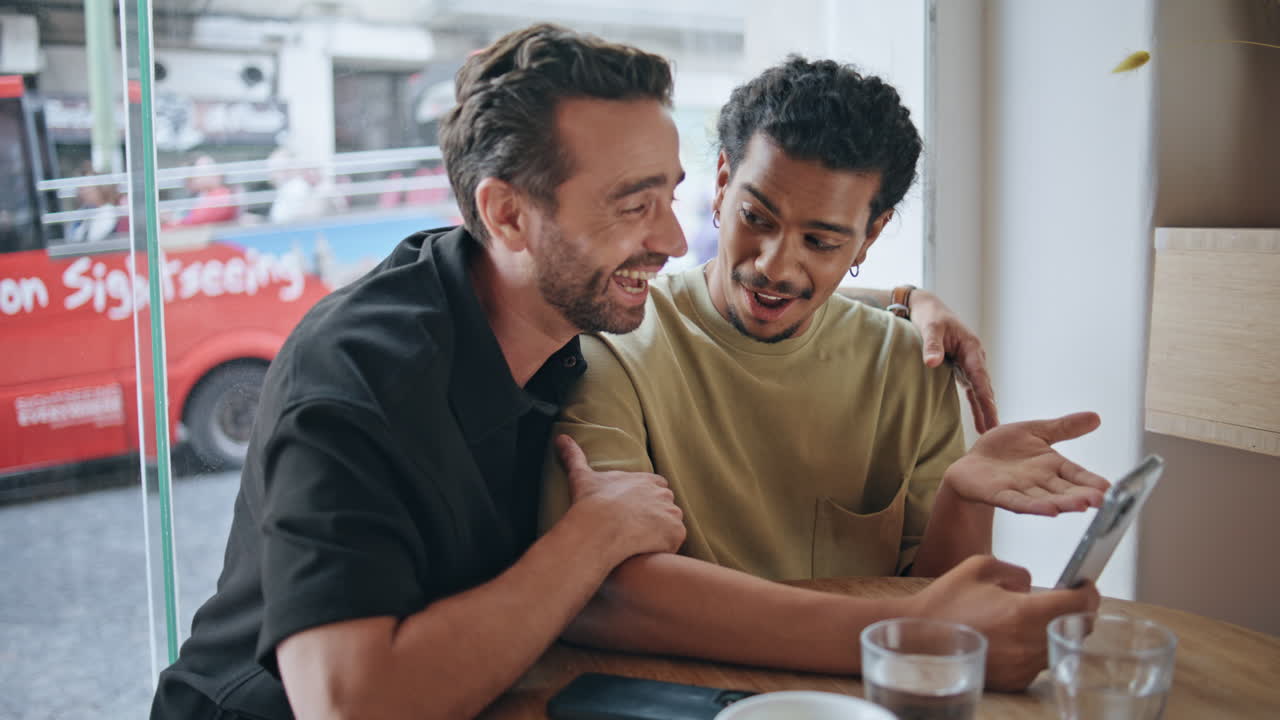 카페테리아에서 스마트폰을 보는 기쁜 동성애자 비디오 통화. lgbti 커플