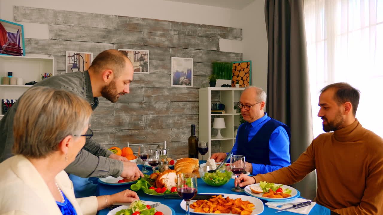 Young man serving his father with a big slice of chicken