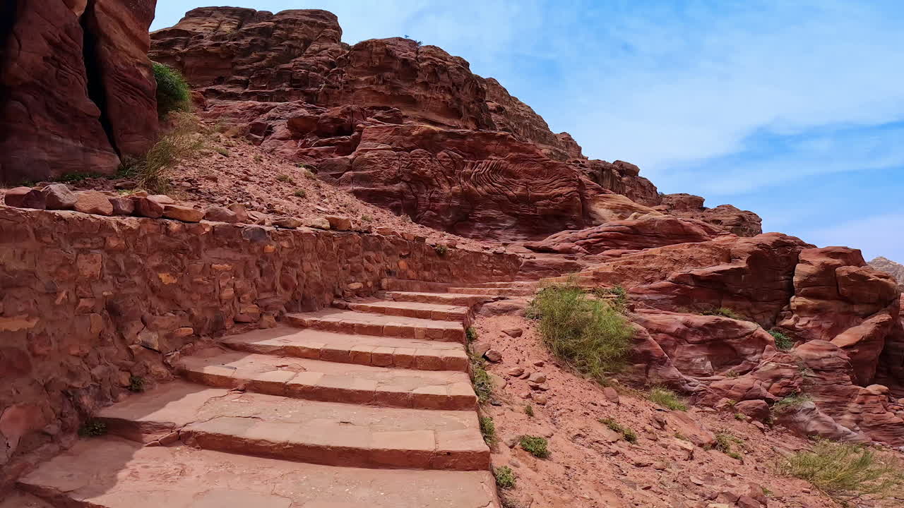 Rising by the stairs in the red rocks. Low angle view it the canyon of Petra, Jordan, West Asia.