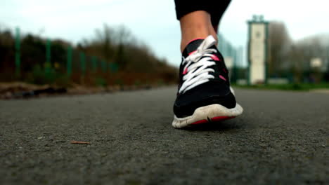 Close-up-of-womans-feet-running-on-path