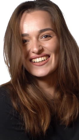 charming model is smiling and posing on a white background in the studio. close-up vertical video