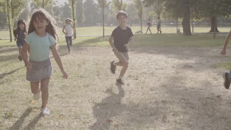 alegres niños multiétnicos corriendo juntos en el parque
